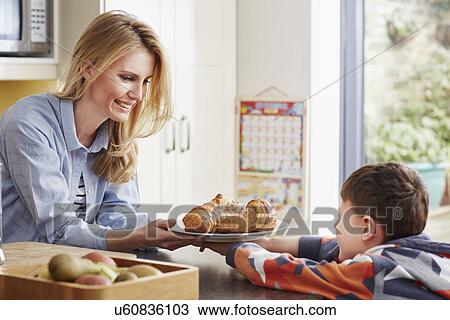 Mother giving son croissant View Large Photo Image Stock Image - Mother giving son croissant. Fotosearch