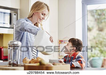 Mother pouring milk into son's breakfast bowl View Large Photo Image Picture - Mother pouring milk into son's breakfast bowl. Fotosearch