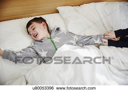 Stock Photograph - Mother pulling son out of bed. Fotosearch