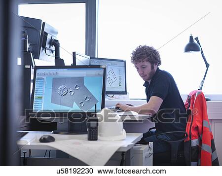 Offshore windfarm engineer working at desk in office View Large Photo Image Stock Image - Offshore windfarm engineer working at desk in office. Fotosearch