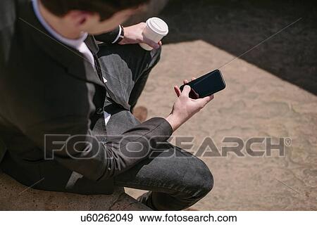 Stock Photo - Over the shoulder view of young businessman reading smartphone texts. Fotosearch