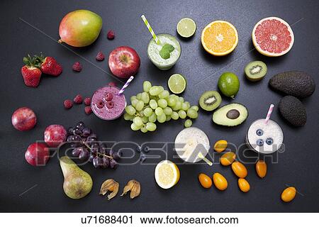 Stock Image - Overhead still life of fresh fruit and smoothies. Fotosearch