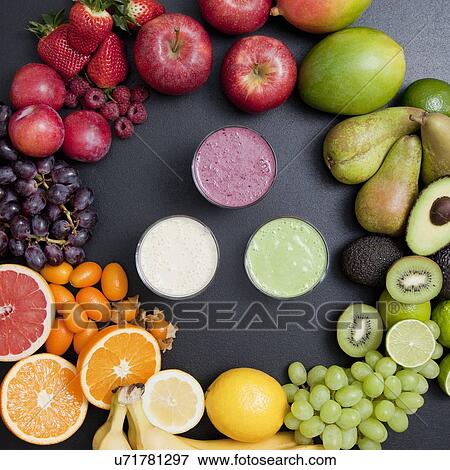 Stock Photo - Overhead still life of variety of fruit surrounding fresh smoothies. Fotosearch