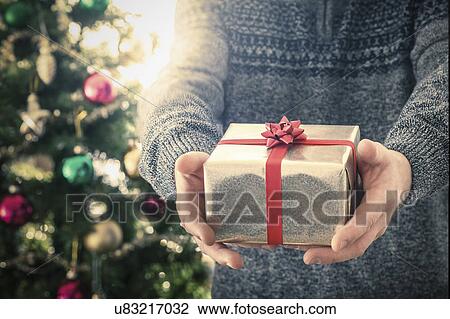 Stock Image - Person holding christmas gift. Fotosearch