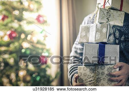 Stock Photography - Person holding stack of christmas gifts. Fotosearch