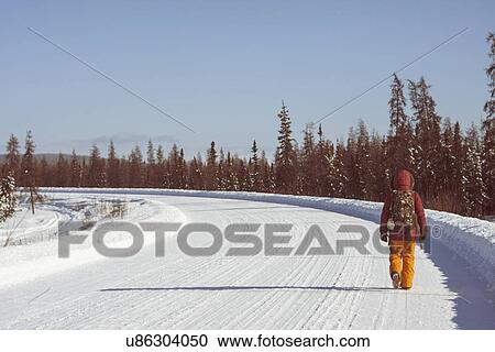 Stock Image - "Person walking on snow covered road, Fairbanks, Alaska". Fotosearch