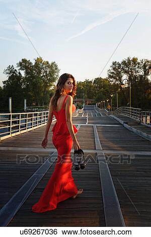 Portrait of a young woman in a smart red dress walking away and looking over shoulder View Large Photo Image Stock Photograph - Portrait of a young woman in a smart red dress walking away and looking over shoulder. Fotosearch