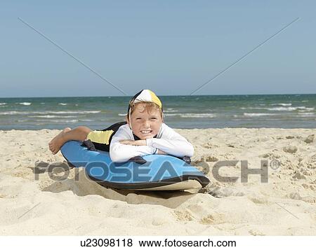 Stock Photo - "Portrait of boy nipper (child surf life savers) lying on surfboard at beach, Altona, Melbourne, Australia". Fotosearch