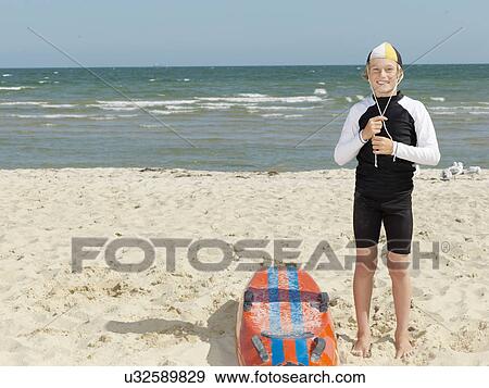 Stock Photo - "Portrait of boy nipper (child surf life savers) fastening cap at beach, Altona, Melbourne, Australia". Fotosearch