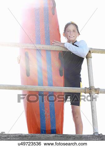 "Portrait of boy nipper (child surf life savers) leaning against railings in sunlight, Altona, Melbourne, Australia" View Large Photo Image Stock Photograph - "Portrait of boy nipper (child surf life savers) leaning against railings in sunlight, Altona, Melbourne, Australia". Fotosearch