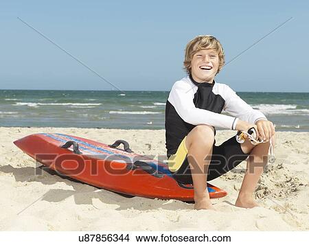 Picture - "Portrait of confident boy nipper (child surf life savers) sitting on surfboard, Altona, Melbourne, Australia". Fotosearch