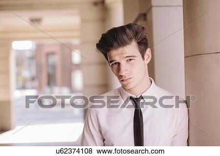 Stock Photo - Portrait of confident young city businessman leaning against pillar. Fotosearch