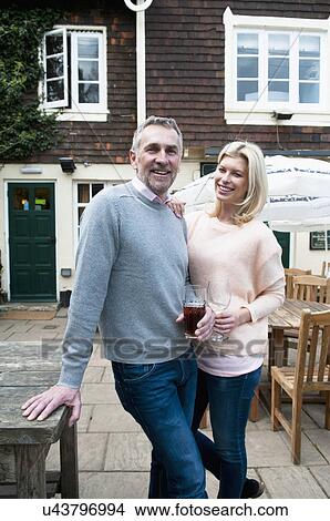Portrait of couple with drinks in front of pub View Large Photo Image Picture - Portrait of couple with drinks in front of pub. Fotosearch