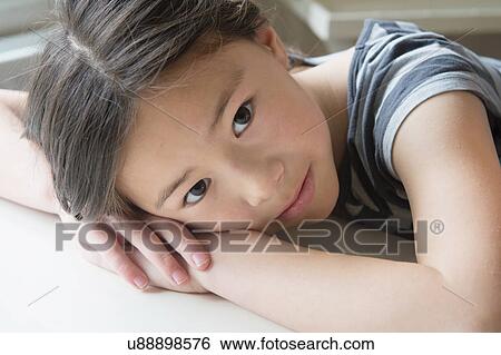 Stock Photograph - Portrait of cute girl resting on hands. Fotosearch