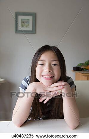 Stock Photography - Portrait of cute smiling girl with chin on hands. Fotosearch