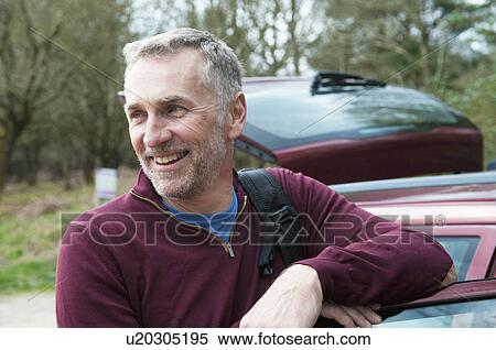 Stock Photography - Portrait of male hiker leaning against car door. Fotosearch