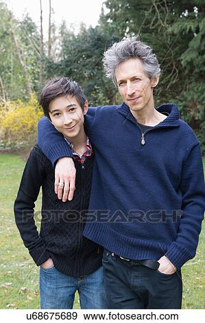 Stock Photo - Portrait of mature man and teenage son in garden. Fotosearch