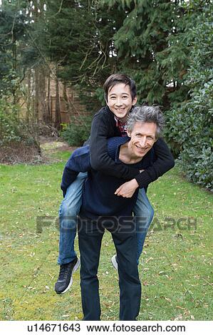 Portrait of mature man giving teenage son a piggy back in garden View Large Photo Image Stock Image - Portrait of mature man giving teenage son a piggy back in garden. Fotosearch