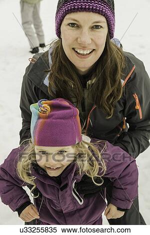 Stock Photography - "Portrait of mother and daughter in snow, smiling, close-up". Fotosearch