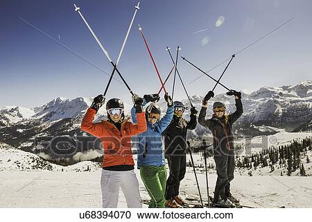 Stock Image - "Portrait of skiers on slope, holding ski poles in the air". Fotosearch