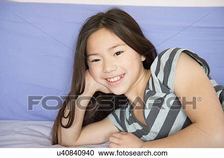 Portrait of smiling girl lying on bed View Large Photo Image Stock Image - Portrait of smiling girl lying on bed. Fotosearch