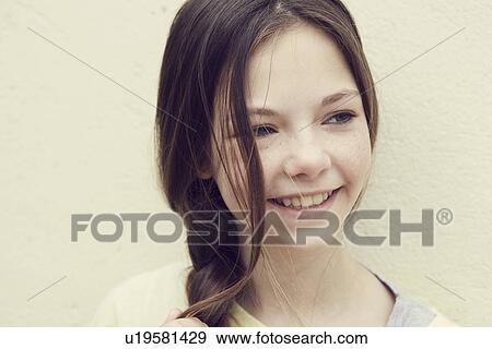 Stock Photo - Portrait of smiling girl with plaited hair in front of wall. Fotosearch