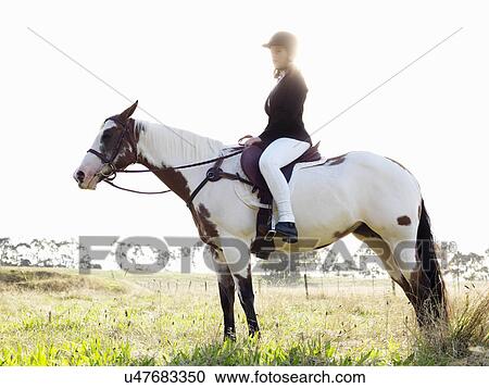 Stock Image - Portrait of teenage girl riding horse in field. Fotosearch