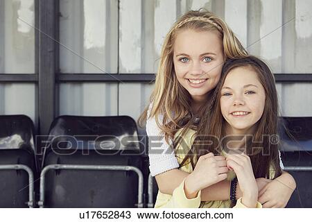 Stock Image - Portrait of two girls hugging in stadium stand. Fotosearch