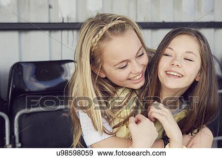 Portrait of two smiling girls hugging in stadium stand View Large Photo Image Stock Photo - Portrait of two smiling girls hugging in stadium stand. Fotosearch