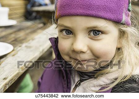 Stock Image - "Portrait of young girl in skiwear, smiling, close-up". Fotosearch