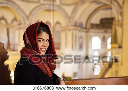 Stock Image - "Portrait of young woman in mosque, wearing headscarf, Istanbul, Turkey". Fotosearch