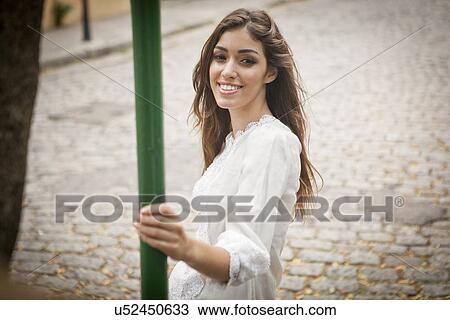 "Portrait of young woman, smiling, holding pole" View Large Photo Image Stock Image - "Portrait of young woman, smiling, holding pole". Fotosearch