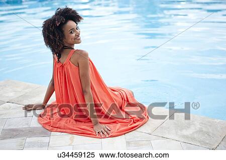 "Portrait of young woman wearing orange dress sitting at hotel poolside, Rio De Janeiro, Brazil" View Large Photo Image Stock Photography - "Portrait of young woman wearing orange dress sitting at hotel poolside, Rio De Janeiro, Brazil". Fotosearch