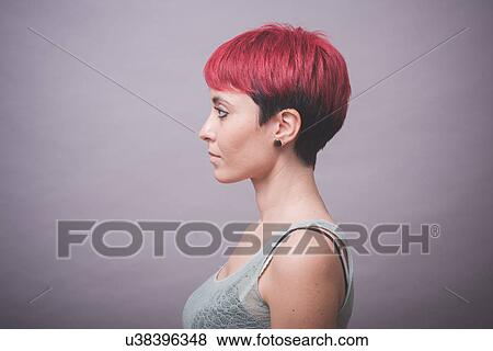 Stock Photo - Profile studio portrait of young woman with short pink hair with hands on cheeks. Fotosearch