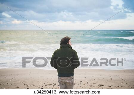 "Rear view of man looking sideways on windy beach, Sorso, Sassari, Sardinia, Italy" View Large Photo Image Stock Image - "Rear view of man looking sideways on windy beach, Sorso, Sassari, Sardinia, Italy". Fotosearch