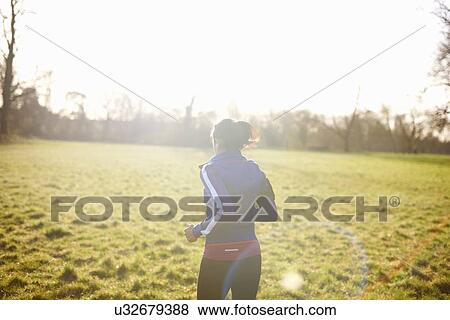 Rear view of mature female runner running in field View Large Photo Image Stock Photo - Rear view of mature female runner running in field. Fotosearch