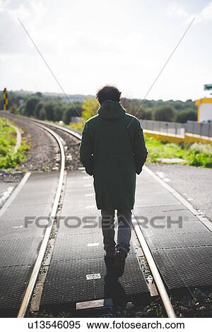 Rear view of mid adult man standing on railway crossing View Large Photo Image Stock Photography - Rear view of mid adult man standing on railway crossing. Fotosearch