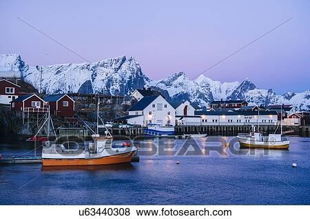 Stock Photo - "Reine fishing village at dusk with snow capped mountains, Norway". Fotosearch