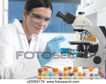 Stock Photo - Scientist holding microscope slide with blood sample in lab. Fotosearch