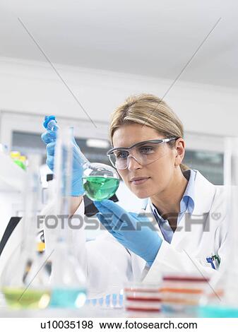 Scientist viewing chemical experiment in a laboratory View Large Photo Image Stock Photo - Scientist viewing chemical experiment in a laboratory. Fotosearch