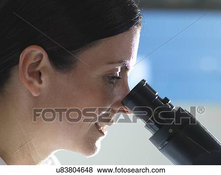 Stock Photo - Scientist viewing cultures under inverted microscope for medical and pharmaceutical research. Fotosearch