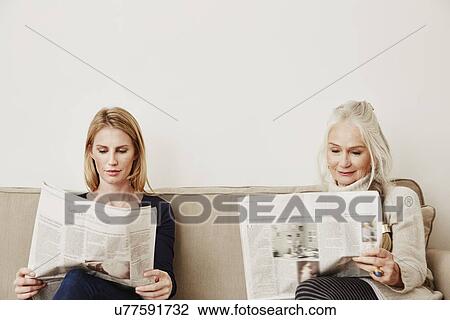 Stock Image - Senior and mid adult women reading newspapers. Fotosearch