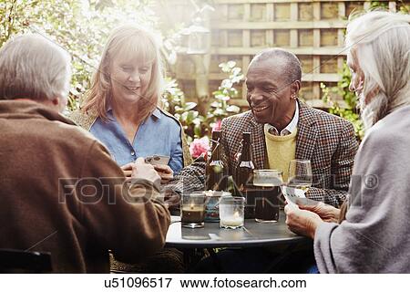 Senior friends drinking and playing cards in garden View Large Photo Image Stock Photo - Senior friends drinking and playing cards in garden. Fotosearch