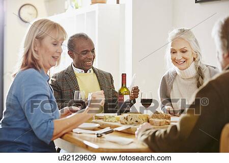 Stock Photo - Senior friends sitting at dinner table. Fotosearch