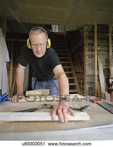 Stock Image - Senior man doing carpentry in workshop. Fotosearch