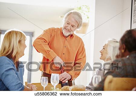 Senior man opening wine with friends View Large Photo Image Stock Image - Senior man opening wine with friends. Fotosearch