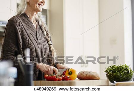 Senior woman preparing food in kitchen View Large Photo Image Stock Photo - Senior woman preparing food in kitchen. Fotosearch