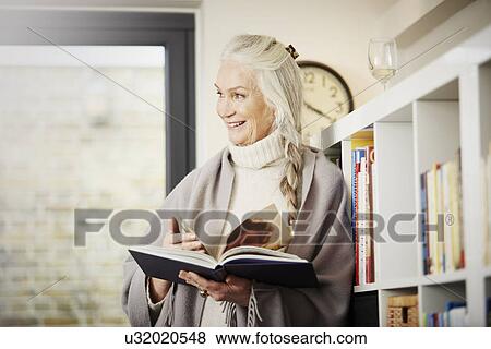 Stock Photo - Senior woman reading book at home. Fotosearch