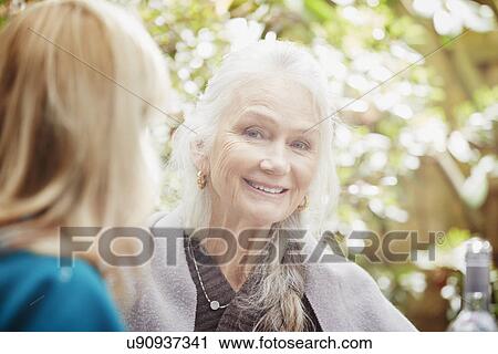 Stock Image - "Senior woman with grey hair in garden, portrait". Fotosearch