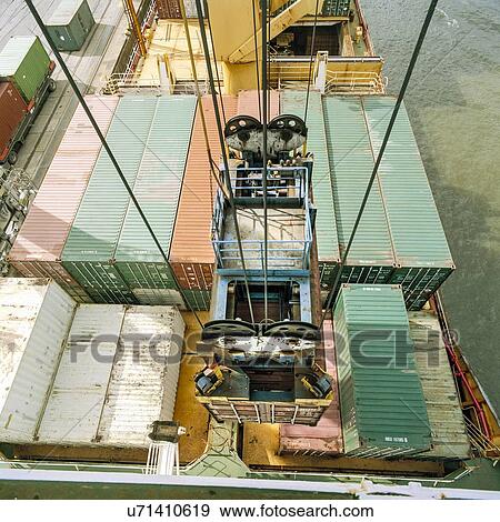 "Shipping container being lowered by crane onto ship in port, high angle view" View Large Photo Image Stock Photo - "Shipping container being lowered by crane onto ship in port, high angle view". Fotosearch